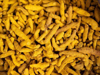 Detailed view of turmeric roots in a market setting, showcasing their vivid yellow color.